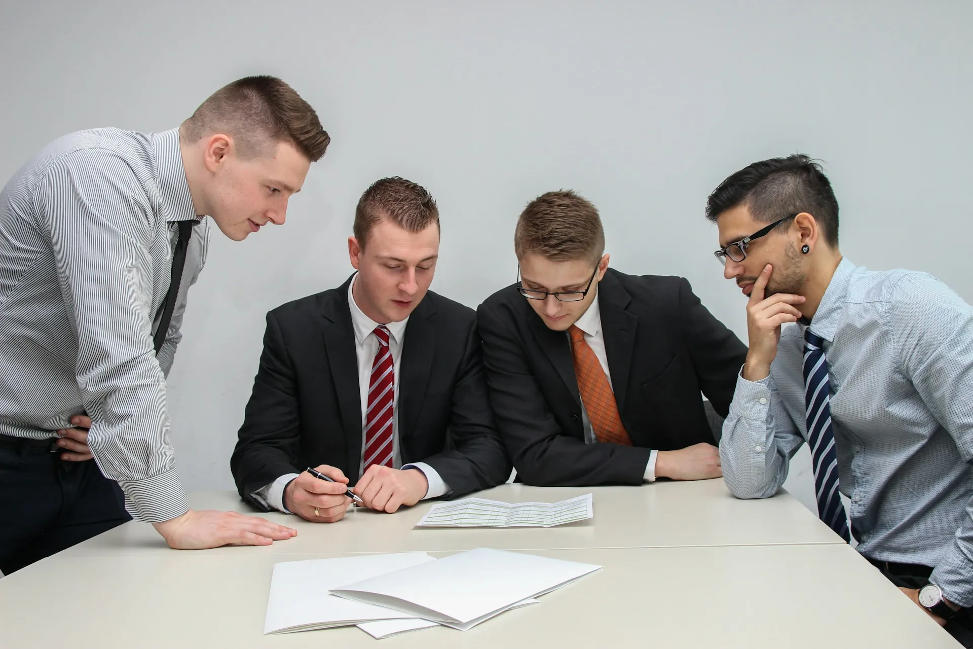 Four colleagues in business attire collaborate and analyze a document together during a meeting in the office.